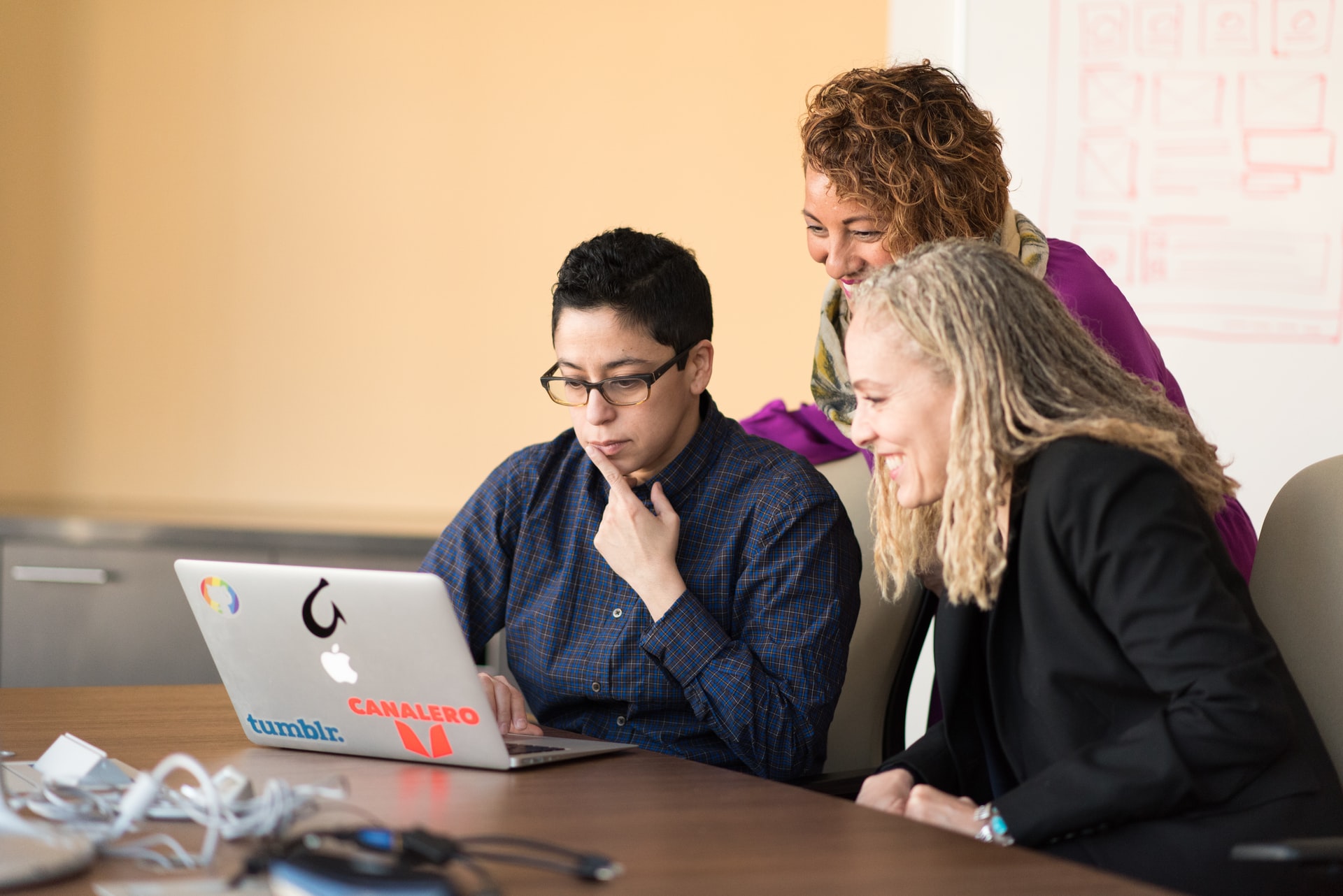 three people looking at the macbook pro