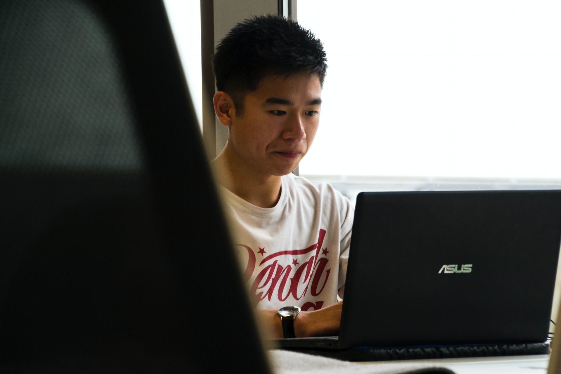 man sitting while using asus laptop