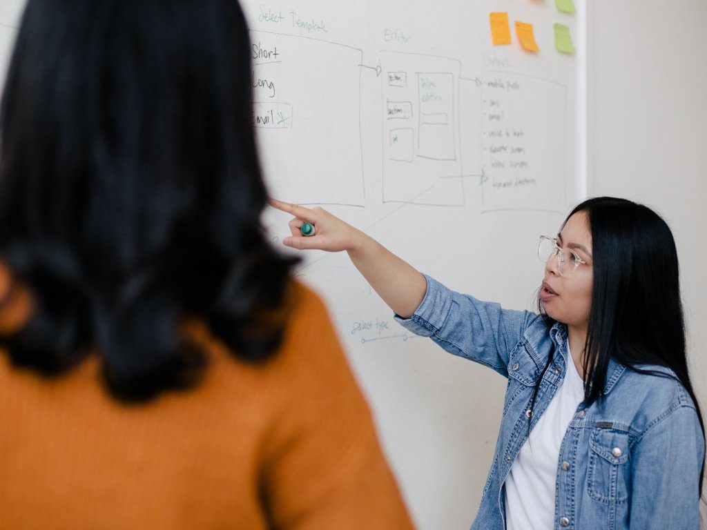 Two women standing in front of whiteboard